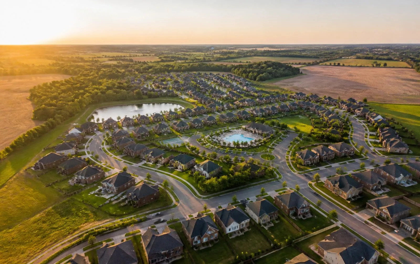 Aerial view of a master-planned community in Union County at golden hour, farmland beyond the rooftops